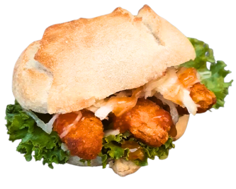 Zu sehen ist ein belegtes Brötchen mit Salat, Zwiebel und knusprig gebackenen Hähnchenstückchen.